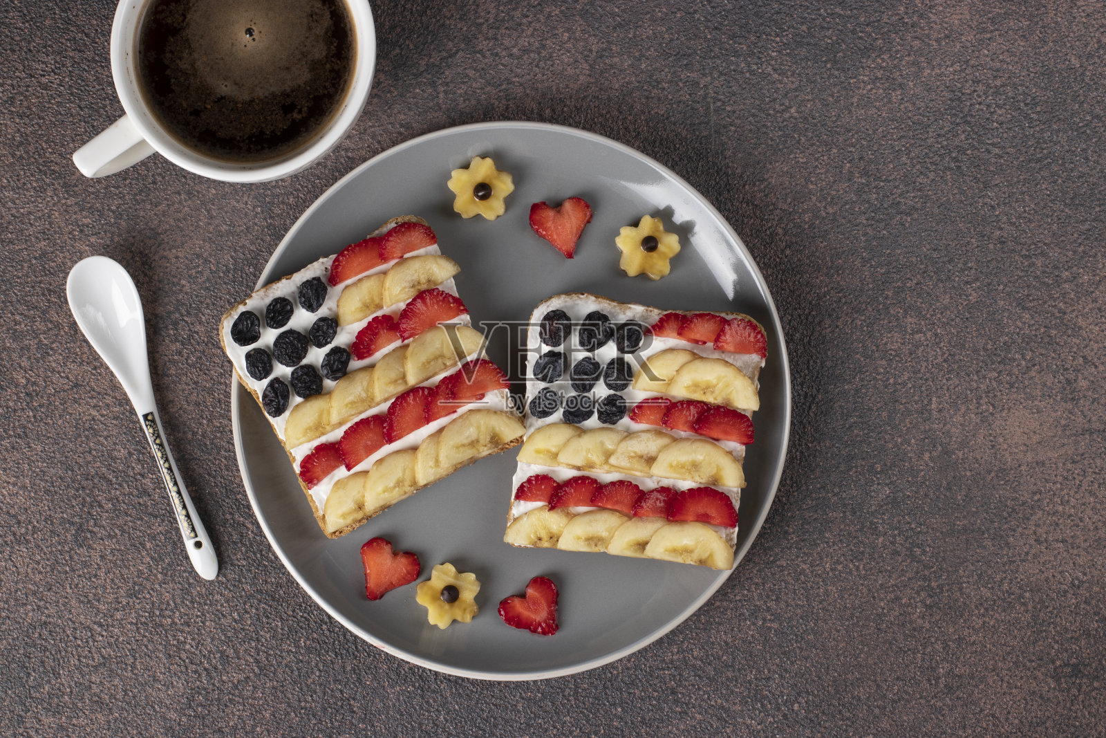 美国国旗三明治，水果和奶油奶酪放在黑麦面包上，一杯咖啡放在灰色盘子里。独立日早餐的创意。俯视图照片摄影图片