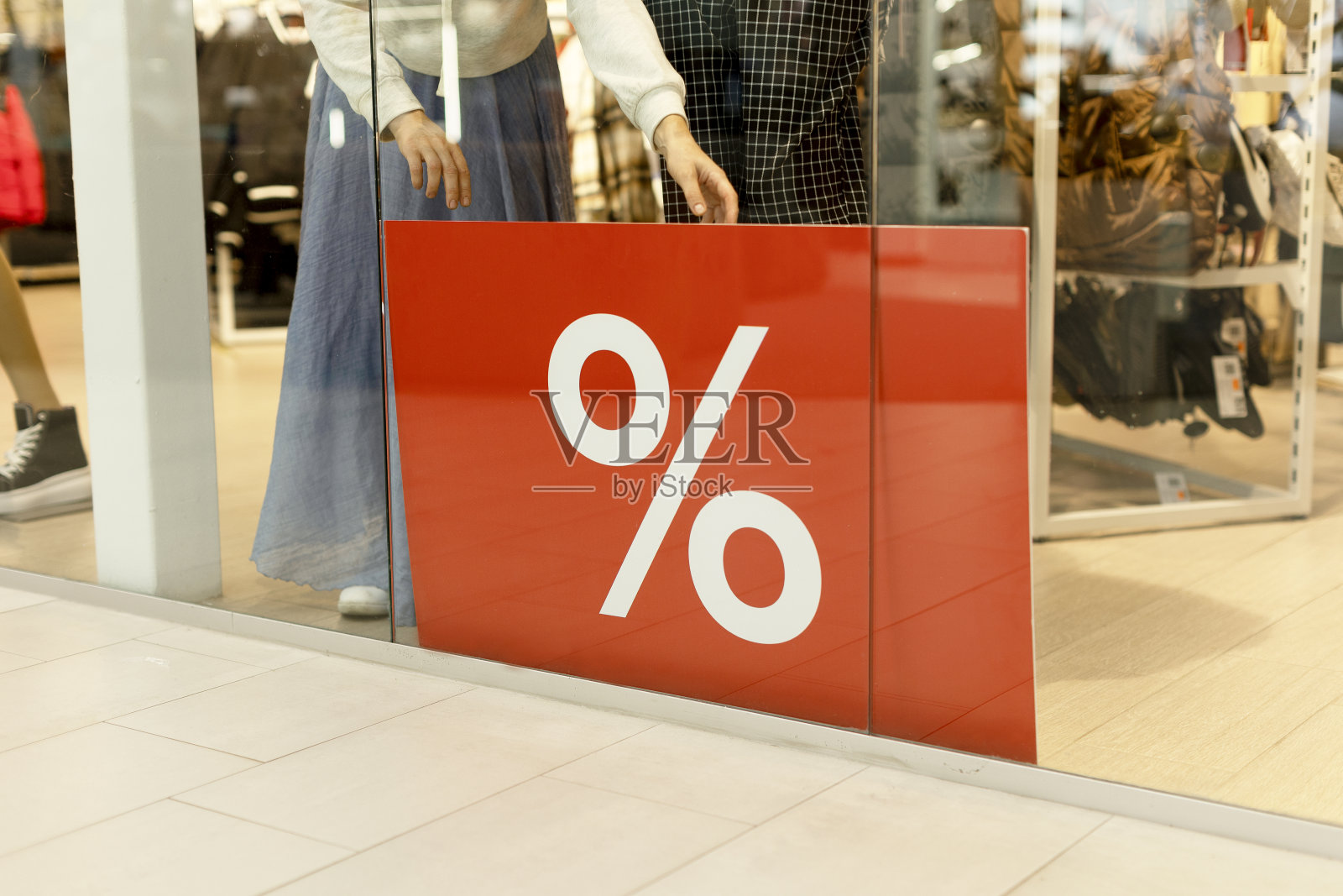 一个女人在商店的橱窗后面挂着一个大横幅，上面写着百分比:Sale照片摄影图片