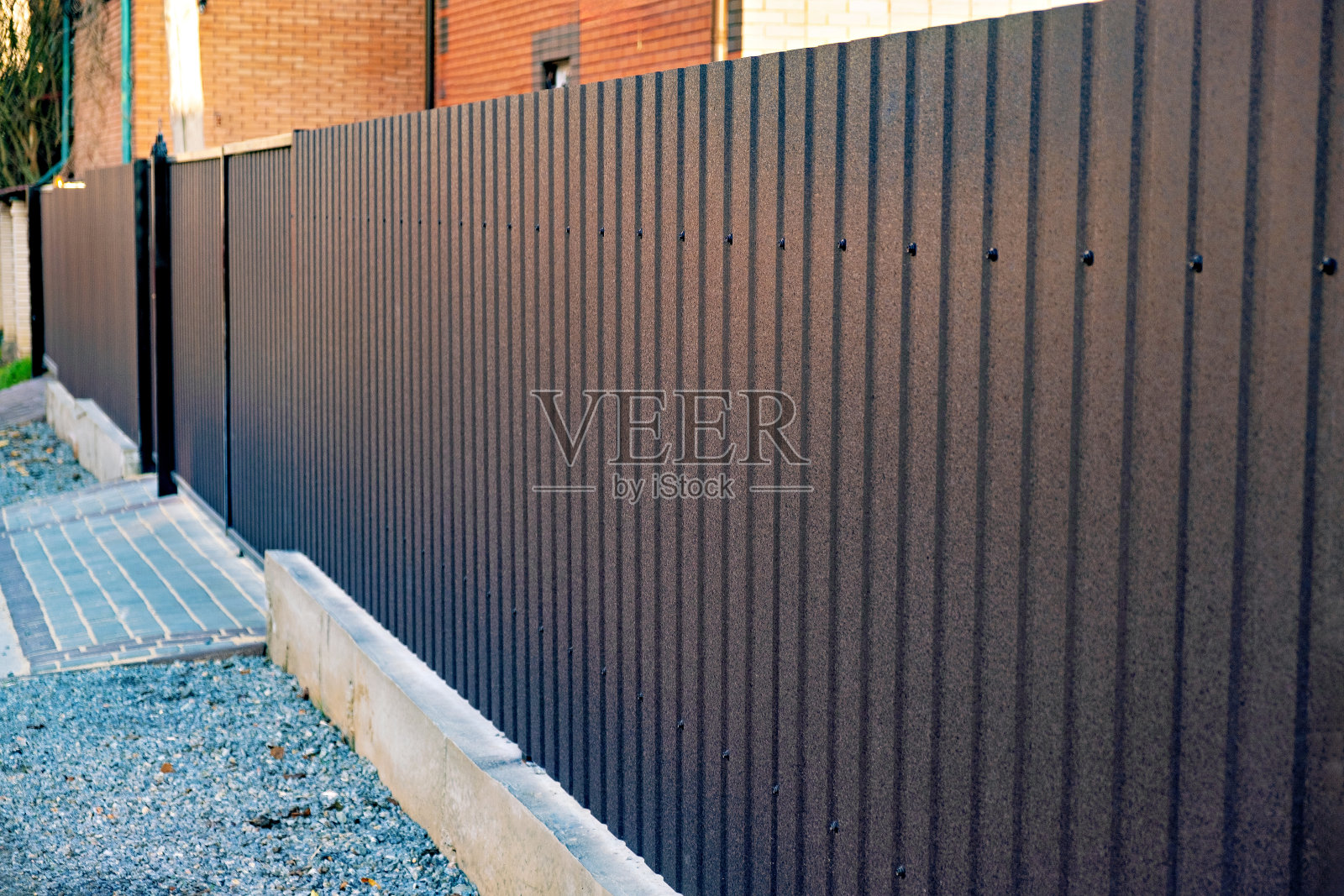 带拱门的砖房前有棕色的栅栏。照片摄影图片