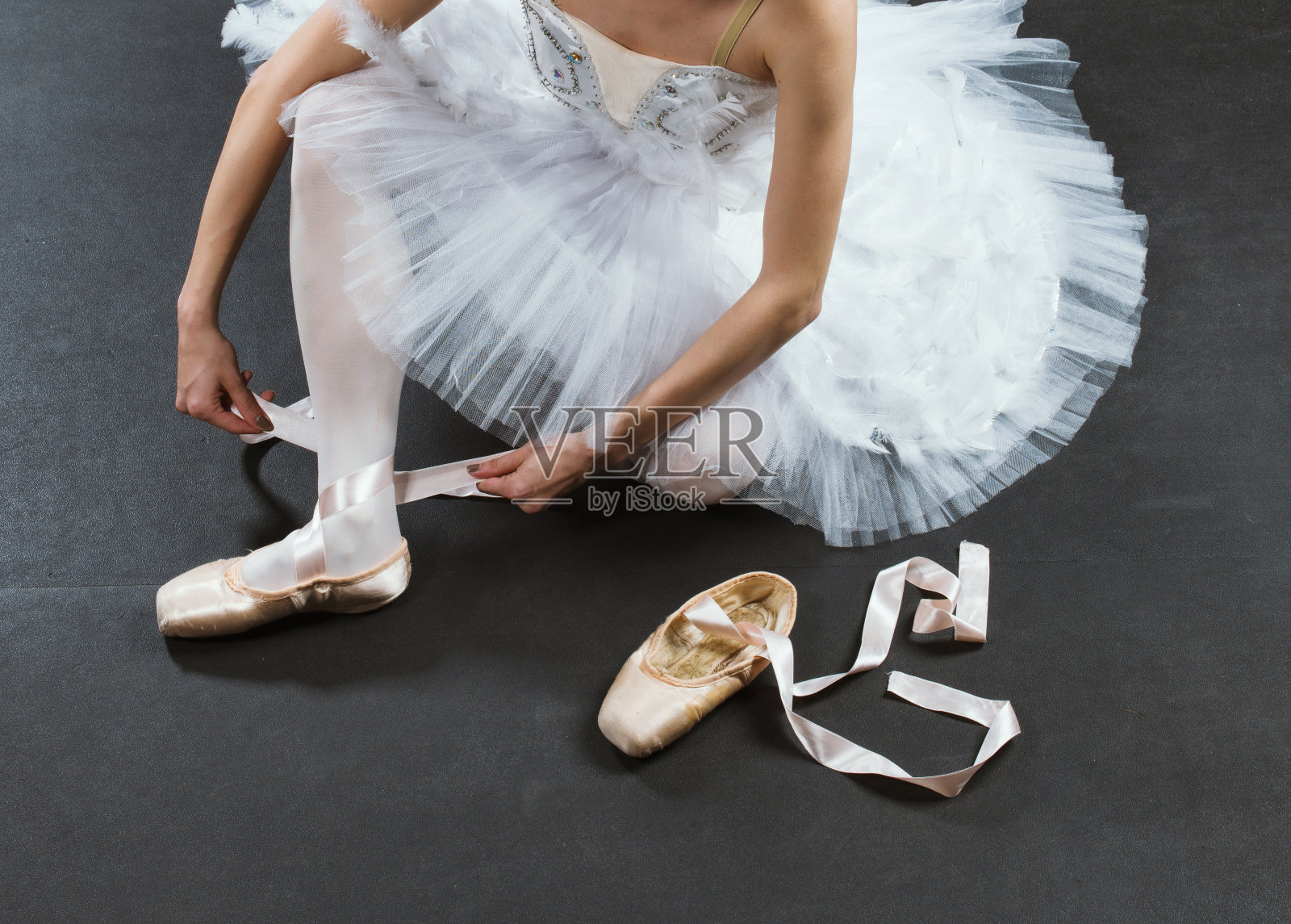 一个年轻的芭蕾舞演员在黑色背景上穿着米色的尖头鞋照片摄影图片