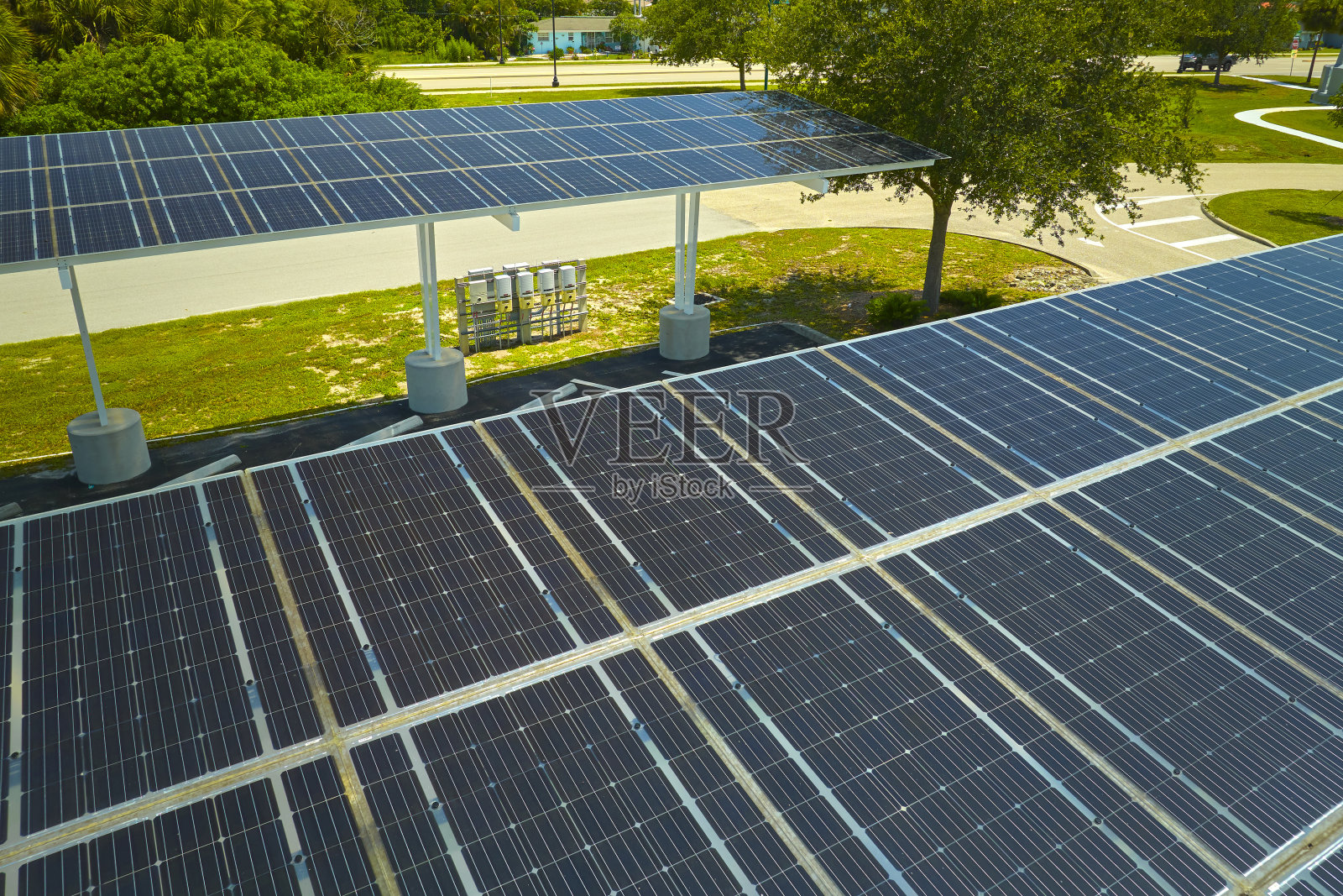 鸟瞰安装在停车场遮阳屋顶上的太阳能电池板，为停放的汽车提供有效的清洁电力。光伏技术融入城市基础设施照片摄影图片