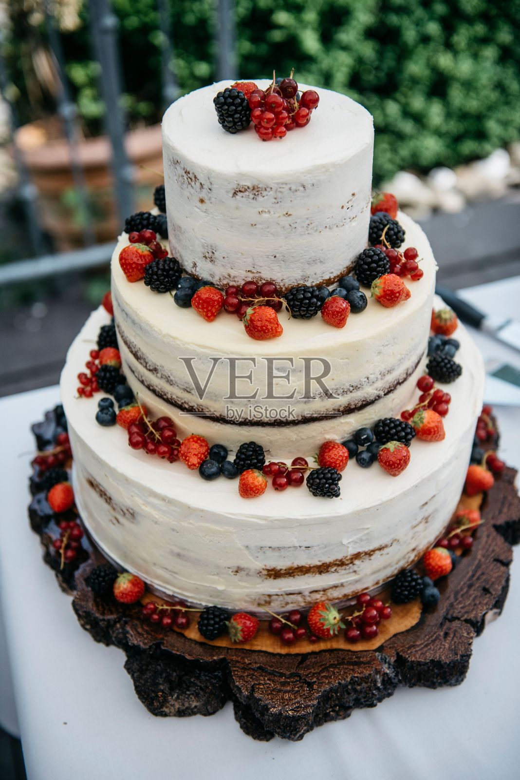 三层婚礼蛋糕装饰着新鲜的浆果，优雅地陈列在桌子上照片摄影图片