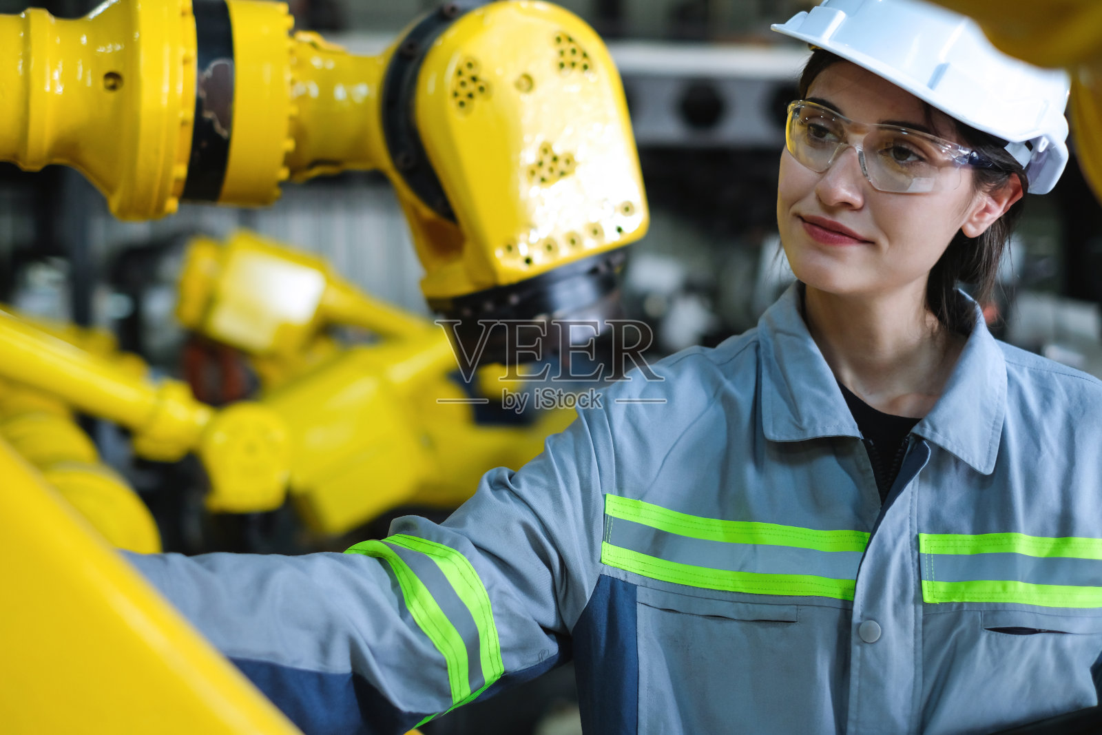 高加索女工厂工程师检查工业机器人手臂，准备提高现代制造业的自动化技术。照片摄影图片