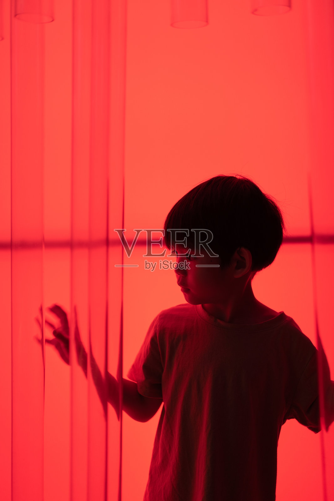 亚洲小男孩，深红色背景。照片摄影图片