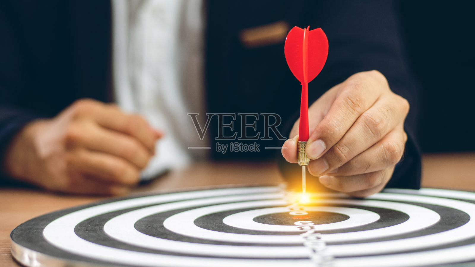 目标经营概念，商人手持飞镖瞄准目标中心经营目标的概念——企业目标定位，焦点概念，隐喻为目标营销或目标箭的概念。照片摄影图片