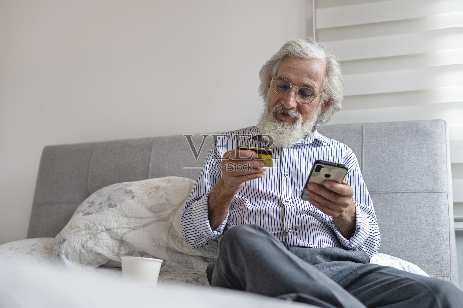 老人在家用信用卡网购。照片摄影图片