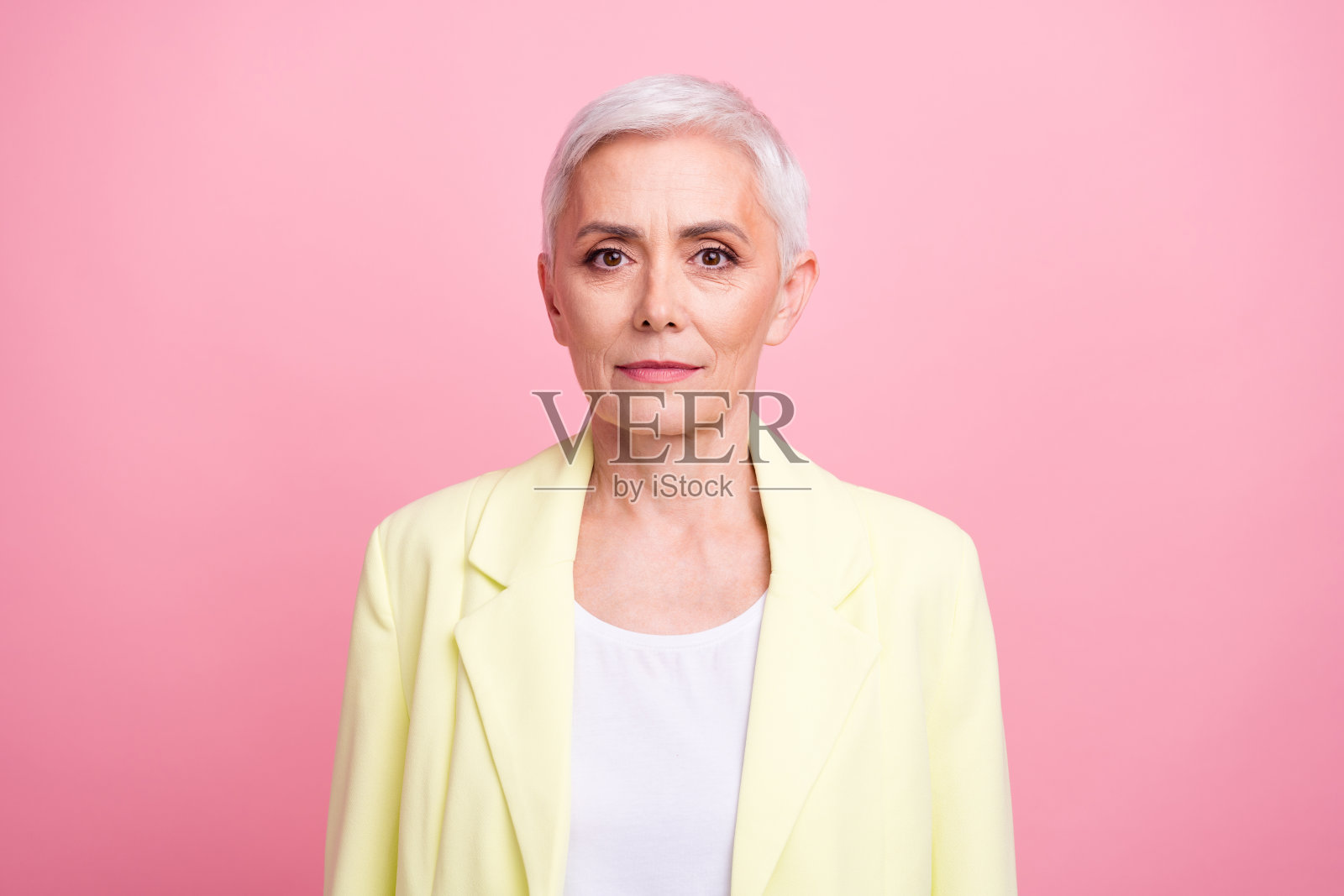 物流公司总经理的肖像成熟年龄白发商务女士在黄色西装孤立在粉红色的背景照片摄影图片