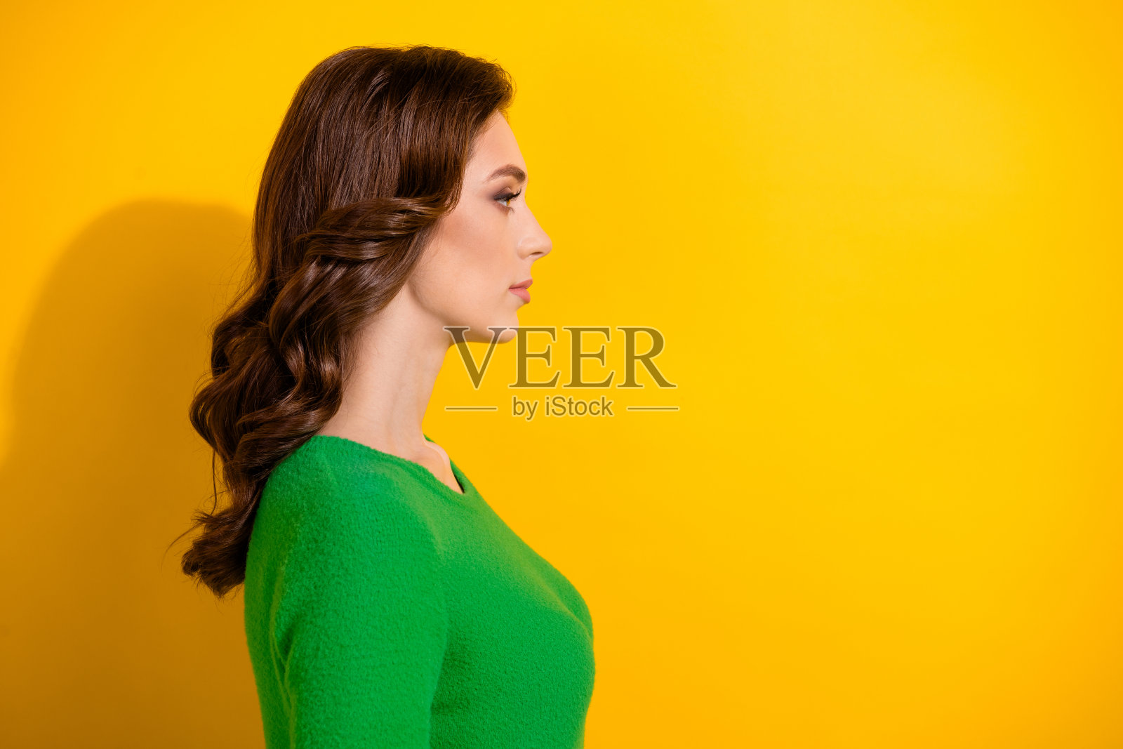 侧面照片，严肃可爱的女孩穿着时髦的衣服，呈现新的发型，黄色背景上的空白空间照片摄影图片