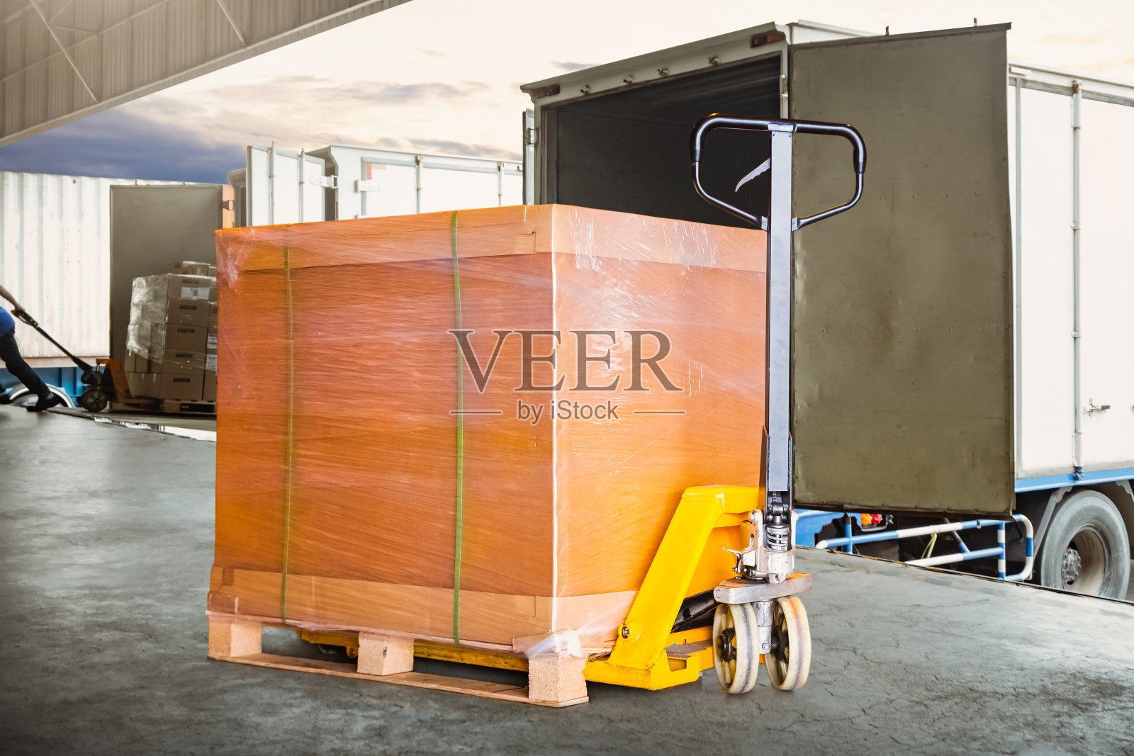 托盘和手摇托盘车上的包装箱。装载到集装箱卡车上。配送、供应、仓储、运输。供应链，运输。货运卡车物流运输。照片摄影图片