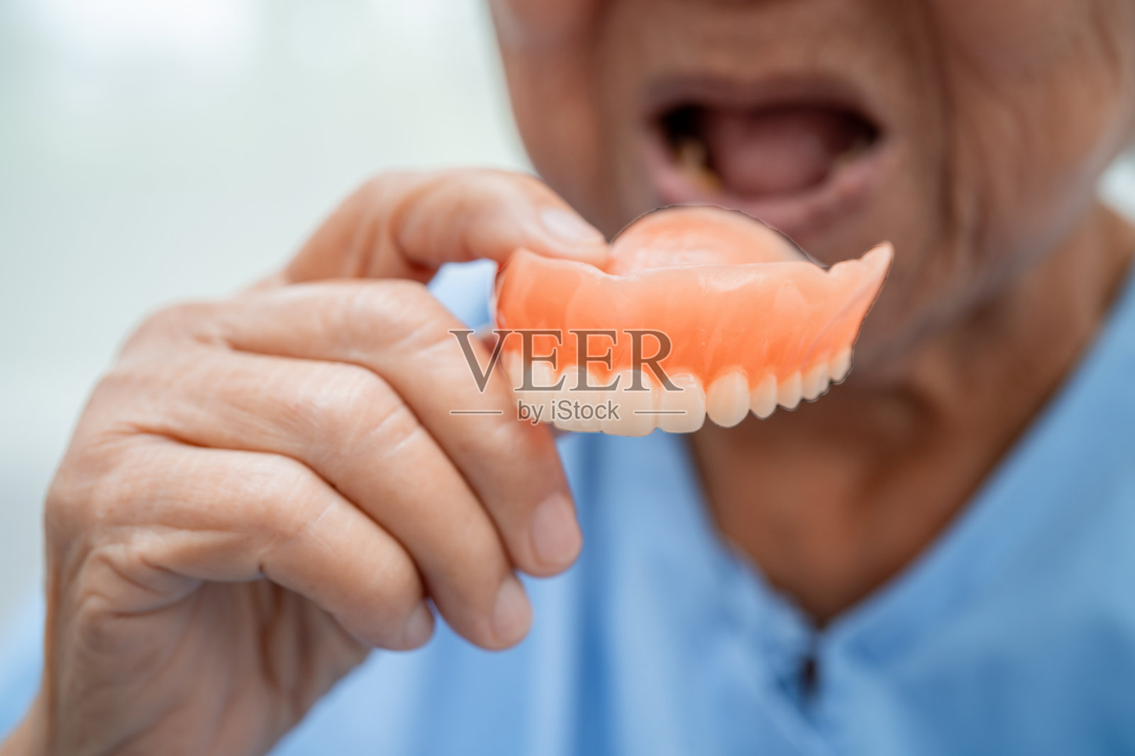 亚洲老年女性患者持用假牙，健康医疗理念强。照片摄影图片