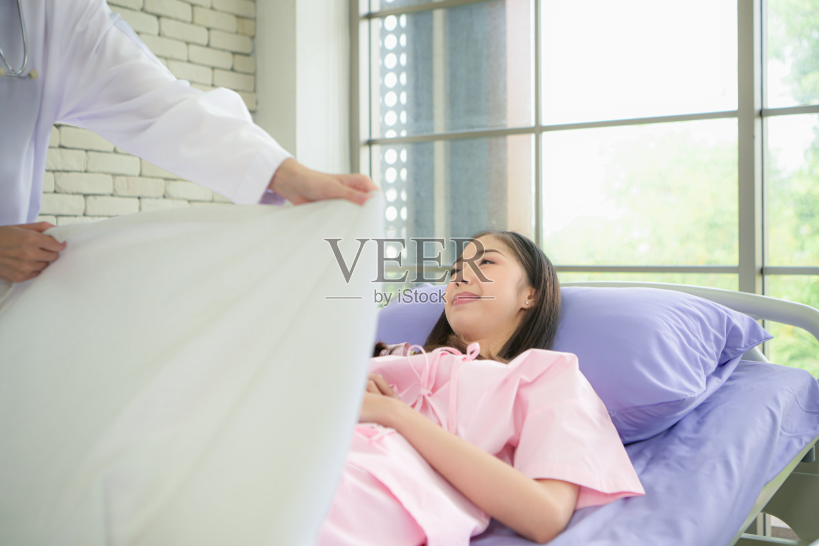 一位女医生帮病人盖上毯子照片摄影图片