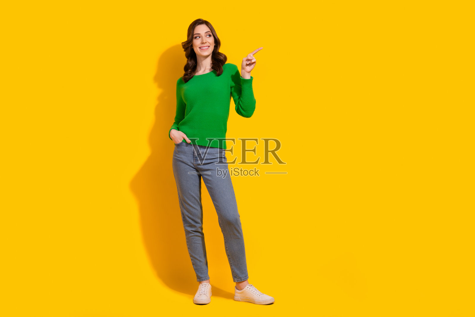 年轻的卷发女友的全身照片指着空白的空间感兴趣的显示效益孤立的黄色背景照片摄影图片