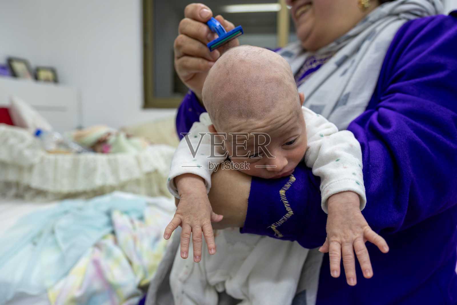 小女孩用剃刀剃头发（满月剃头）照片摄影图片