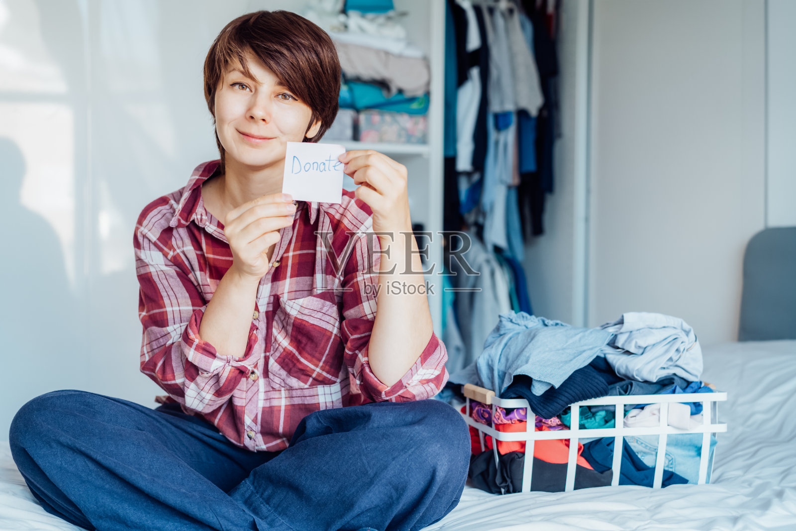 微笑的女人整理衣物捐赠给慈善机构，整理、分类衣物，重复利用旧物，可持续消费理念照片摄影图片