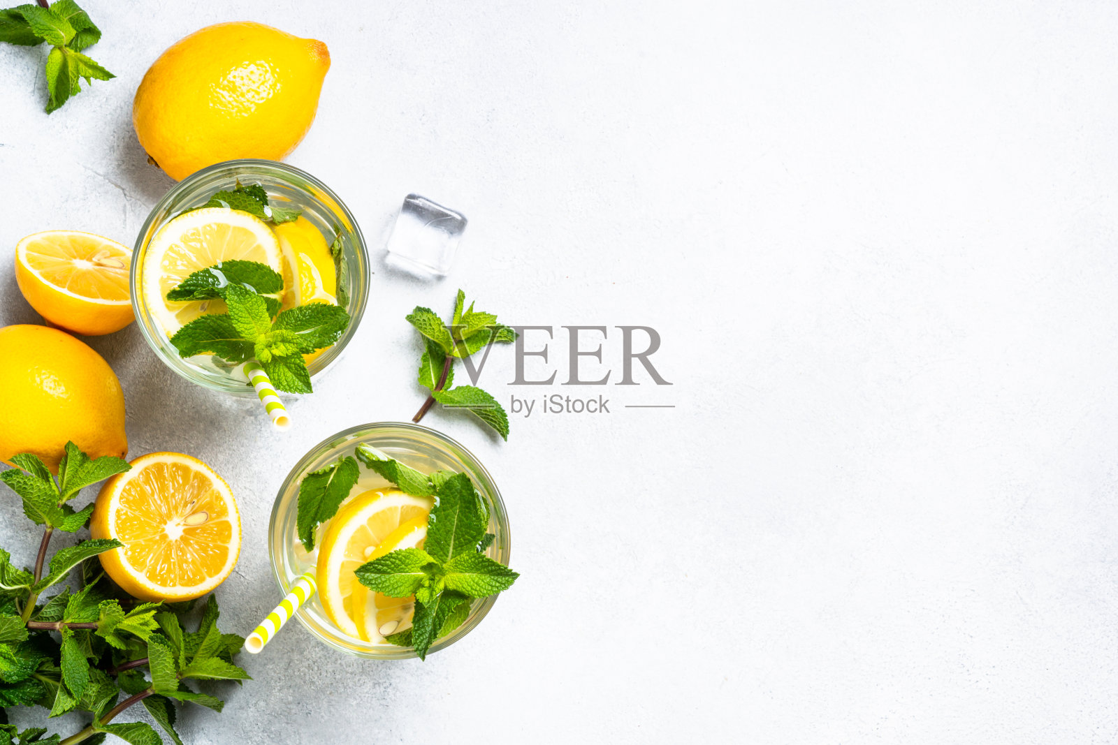 白色桌子上玻璃杯里的柠檬水。照片摄影图片