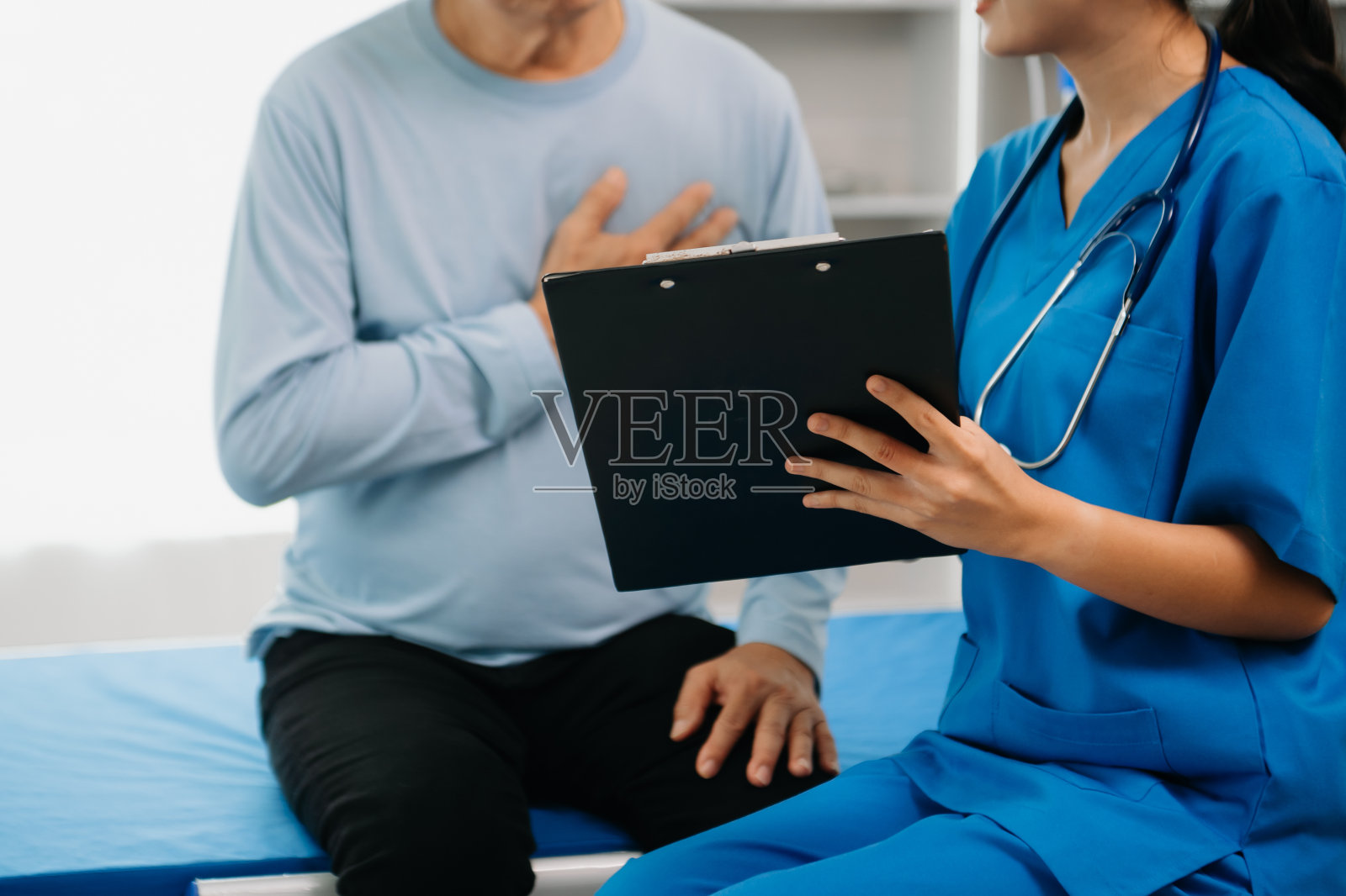 主治医师坐在检查床上有说有笑地与男病人讨论治疗照片摄影图片