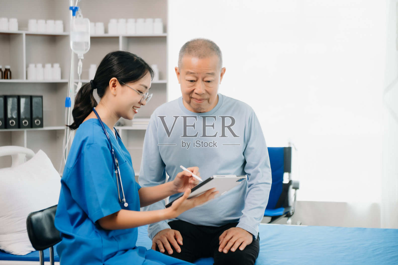 主治医师坐在检查床上有说有笑地与男病人讨论治疗照片摄影图片