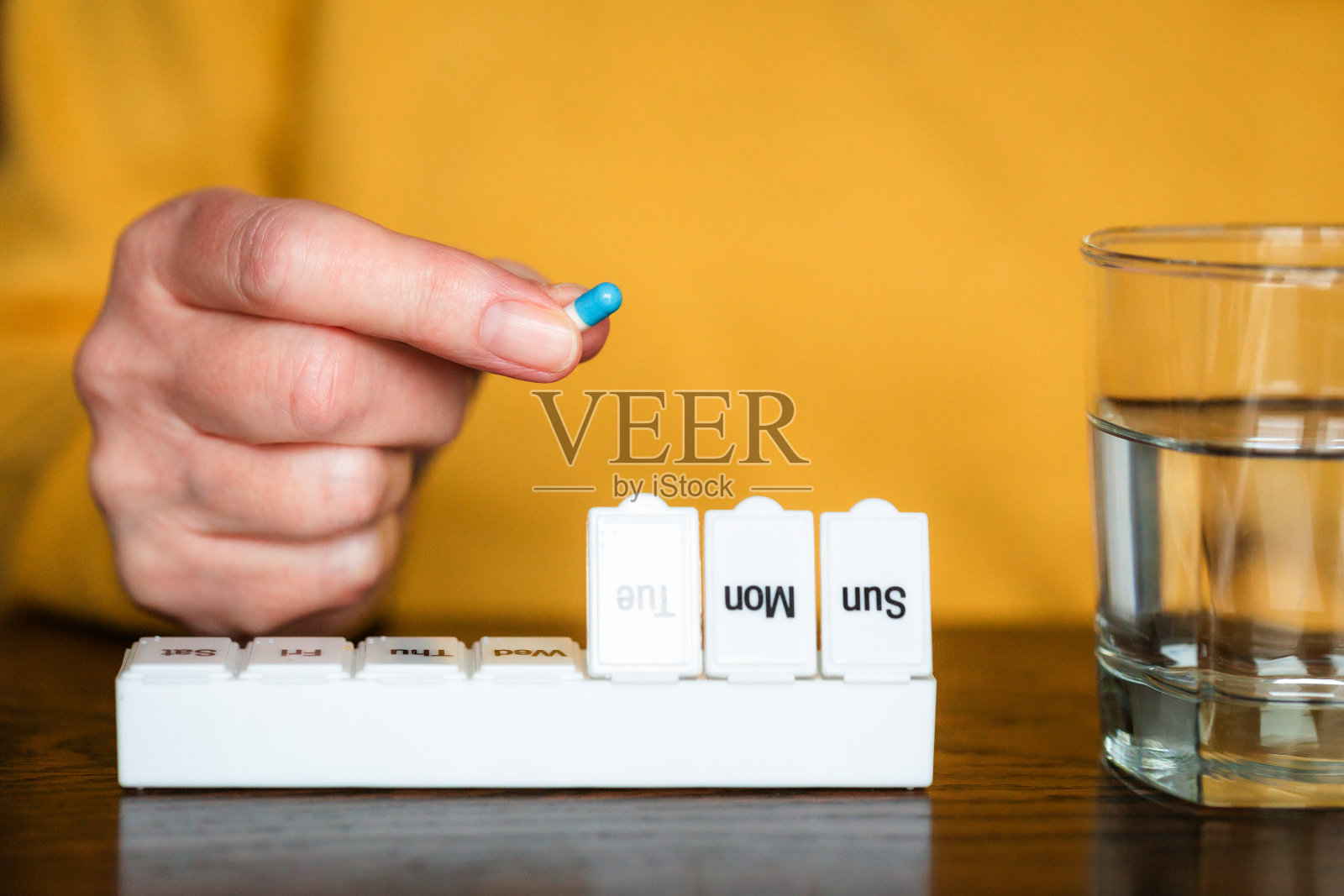 老年妇女将药物整理进日常药盒的特写照片摄影图片