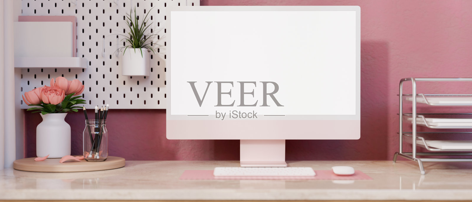 一个可爱的粉色女性办公桌，粉红色的墙上有一个白色屏幕的电脑模型。照片摄影图片