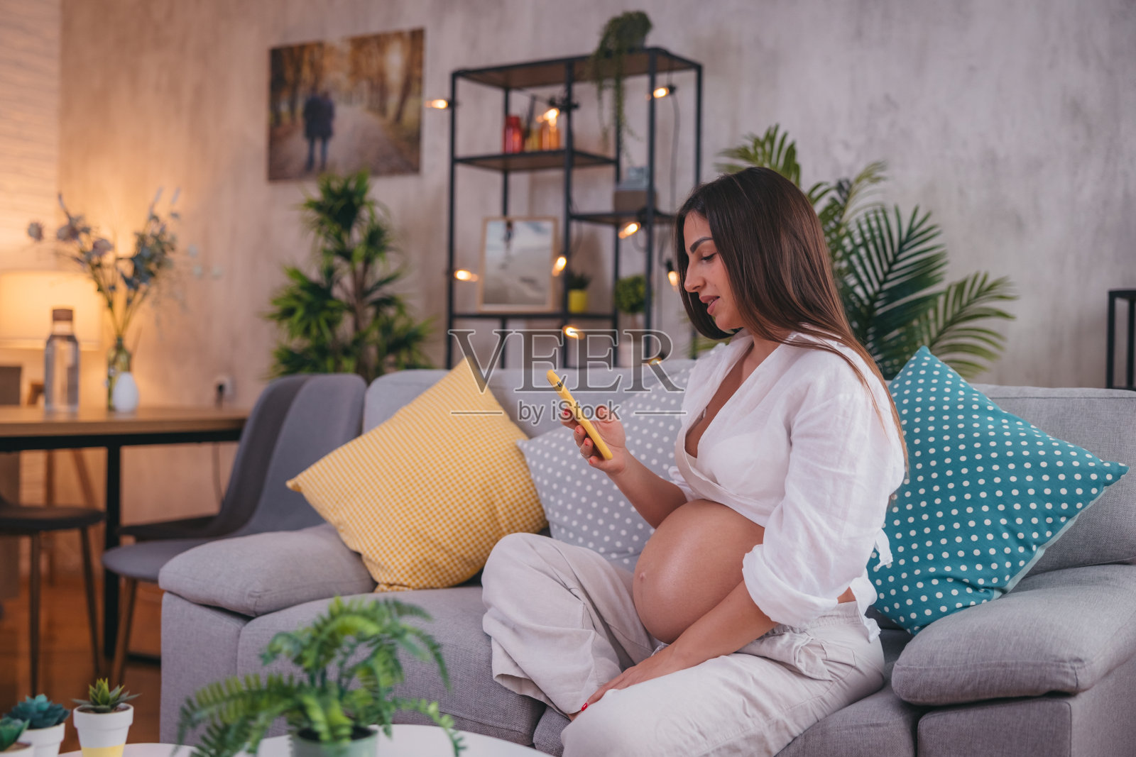 美丽的孕妇在家里使用她的智能手机照片摄影图片