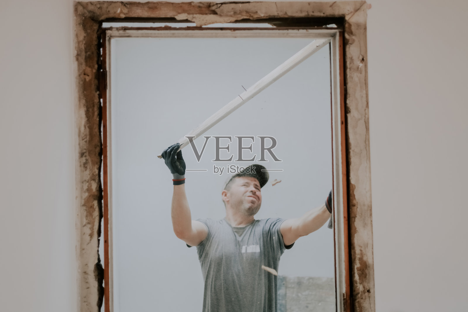 一个人在门口用撬棍干活。照片摄影图片