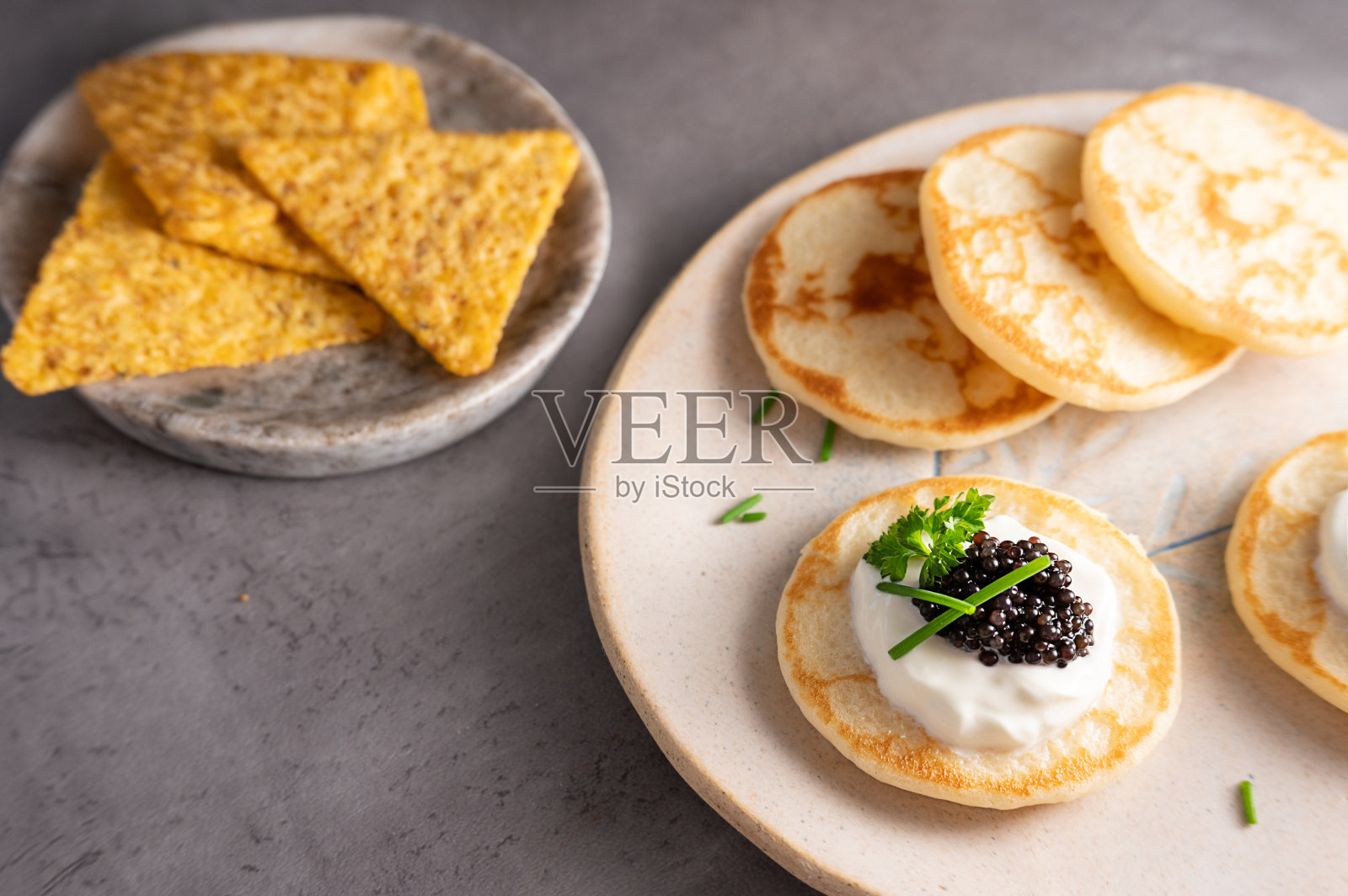 煎饼或迷你薄饼配上黑鱼子酱和酸奶油。照片摄影图片
