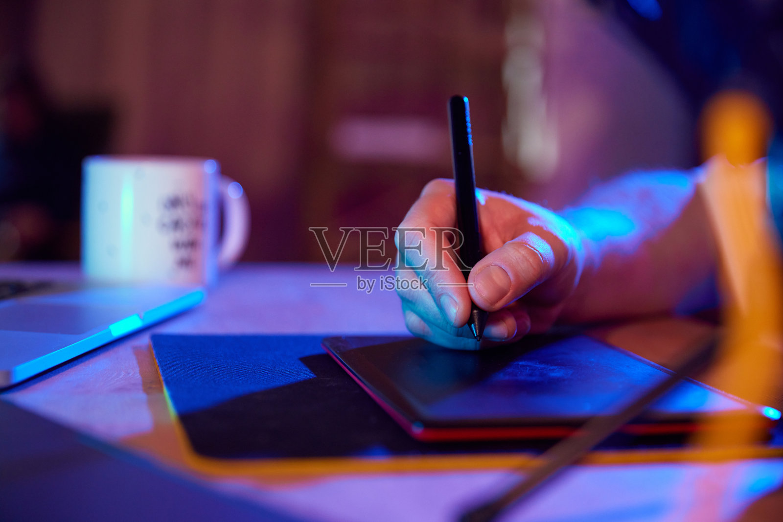 男性手绘在数字画板上，在充满活力，照明的工作空间。内容创造者和创造性职业。照片摄影图片