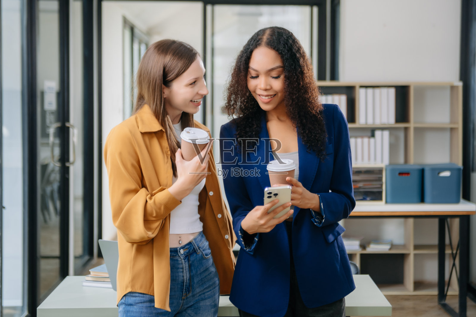 两个快乐的女商人在共同工作的办公室里拿着咖啡杯照片摄影图片