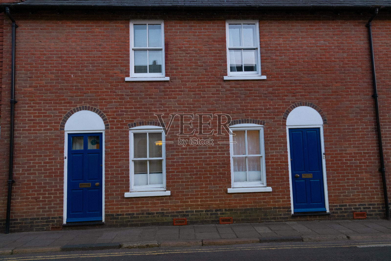 一座红砖砌成的连栋房子，装饰着醒目的蓝门和白窗照片摄影图片