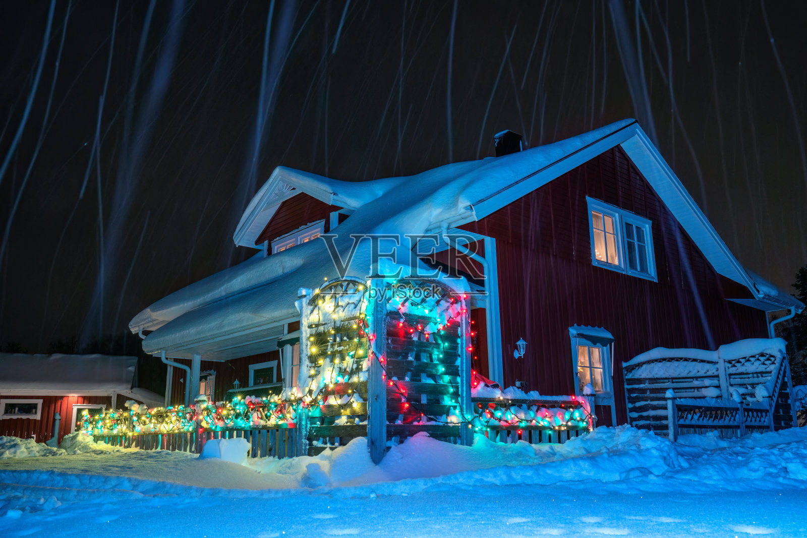 风景如画的圣诞节装饰的房子有许多五颜六色的灯。大雪过后屋顶上积了很多雪。有雪迹的夜照照片摄影图片