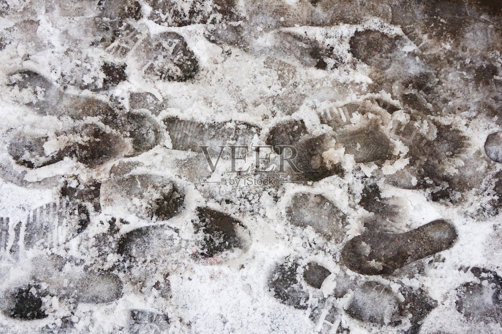 冬季路面状况不佳。泥泞的小路。鞋子痕迹。湿雪融化。人行道上覆盖着湿雪。照片摄影图片