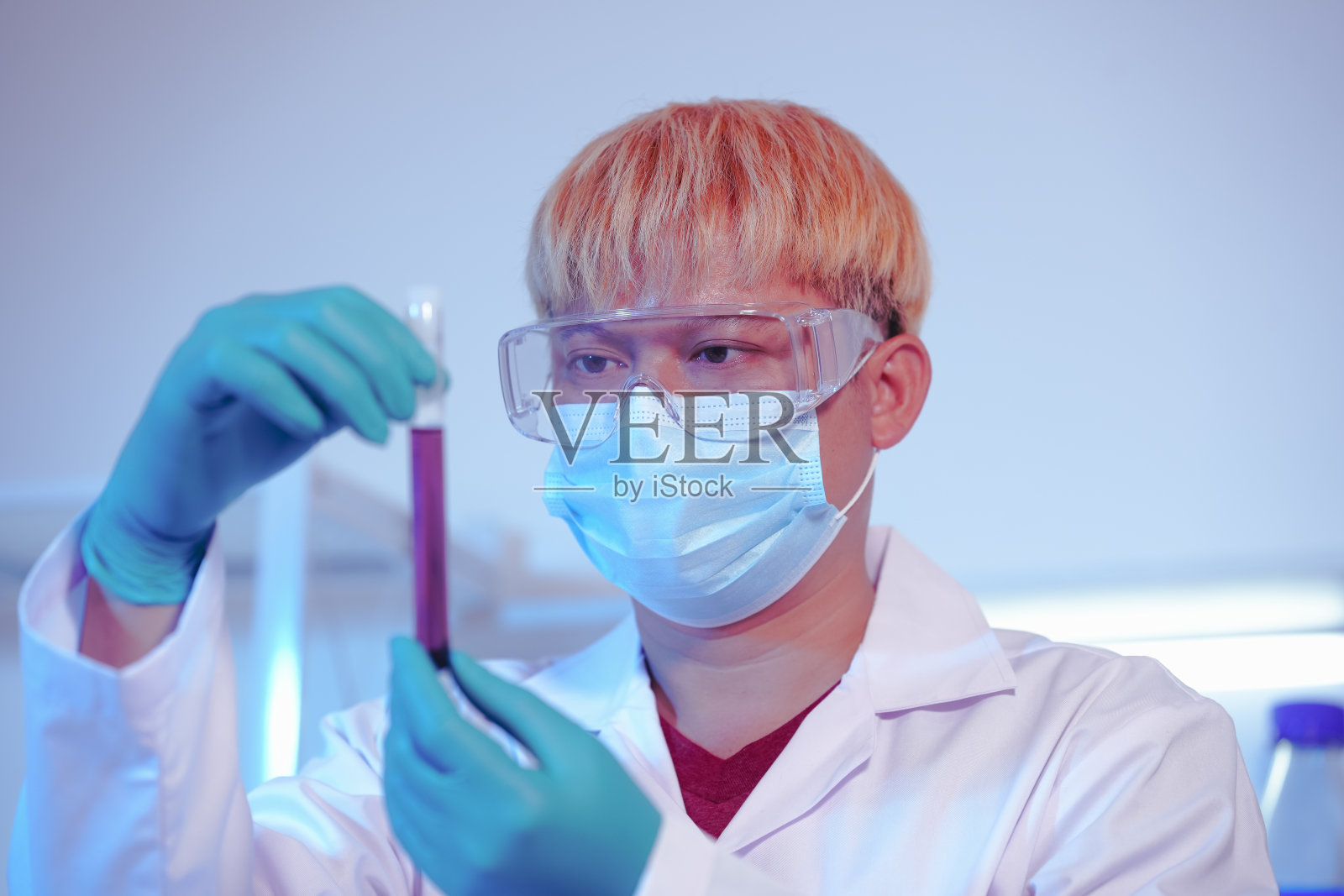 一位亚洲中年男性科学家在实验室里进行研究，周围摆满了培养皿和烧杯。研究汽油、食品成分、香水、病毒和药物的化学成分照片摄影图片