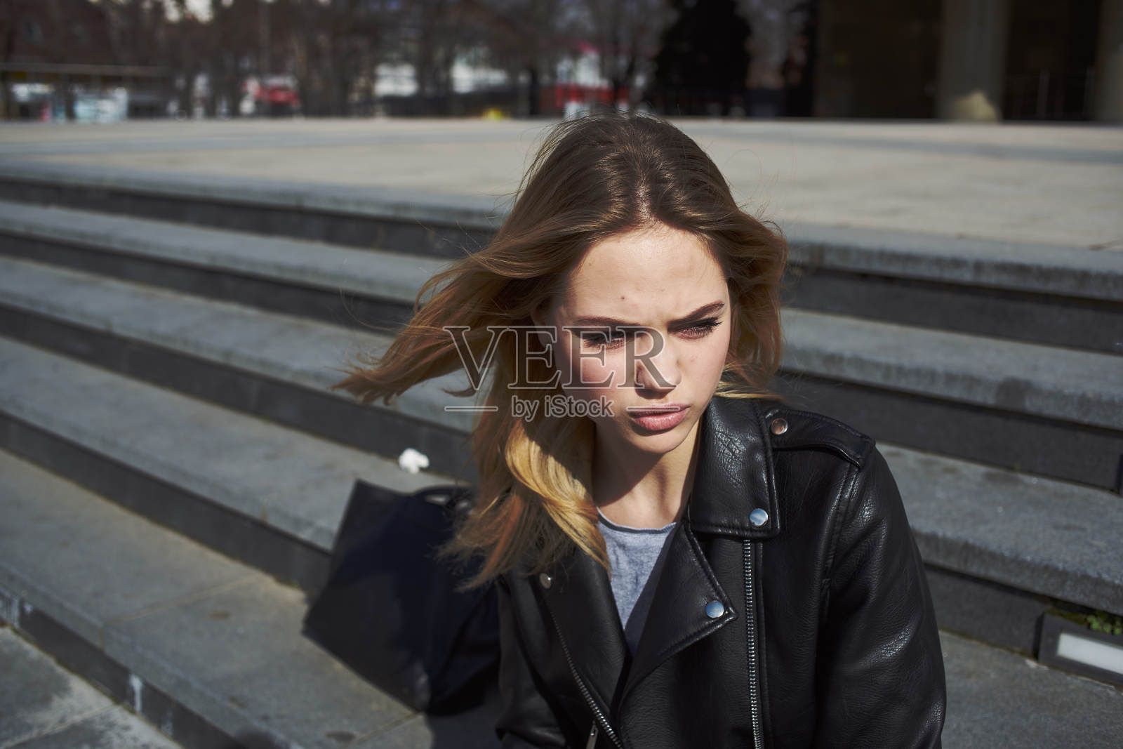 秋天，女模特坐在街上一栋建筑物附近的楼梯上照片摄影图片