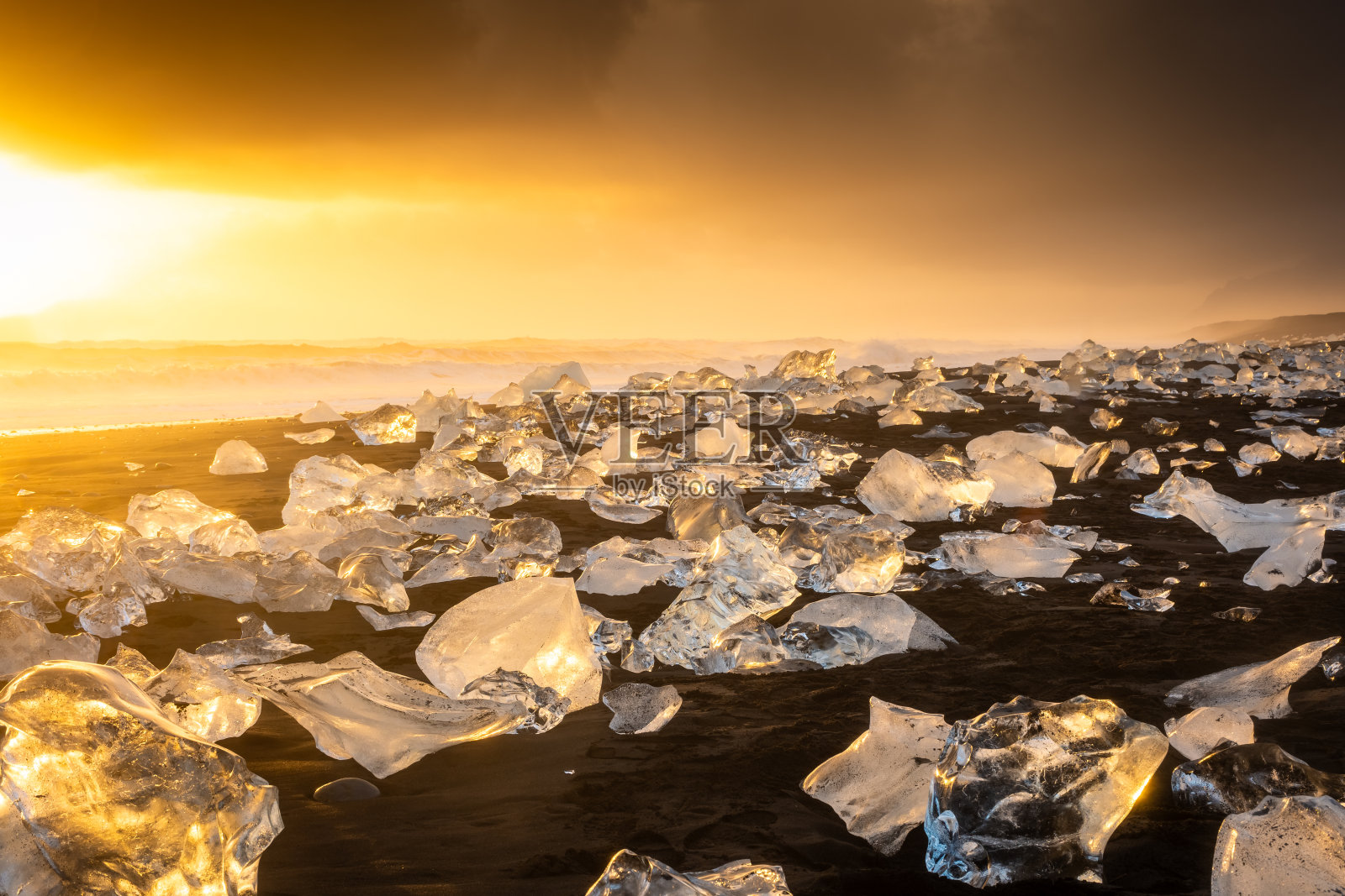钻石海滩上令人惊叹的日落，火山黑色海滩和Jokulsarlon冰川泻湖的冰山，冰岛照片摄影图片