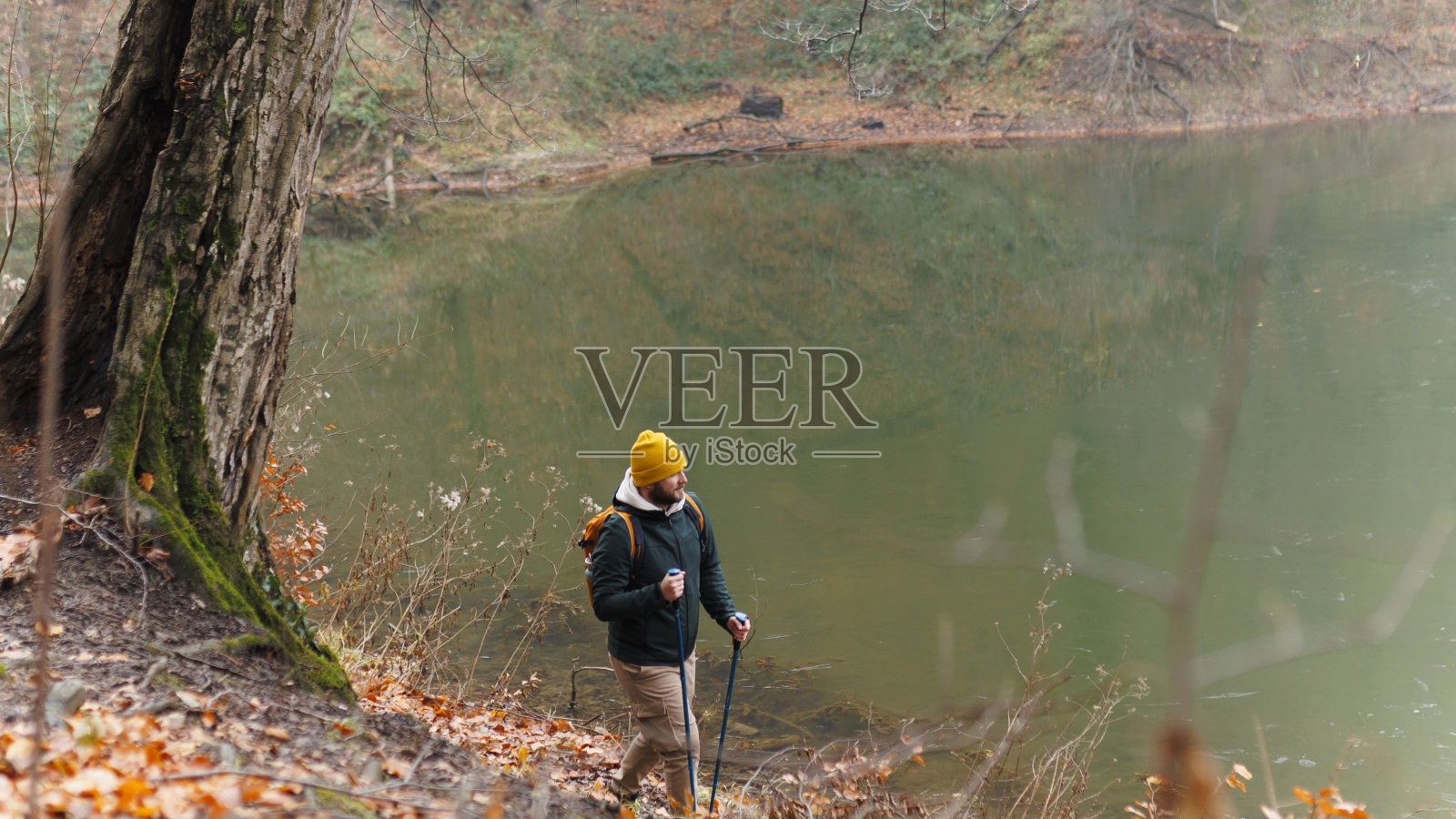 自信的年轻人在山上行走，他拄着登山杖，背着背包，自由和运动的理念照片摄影图片