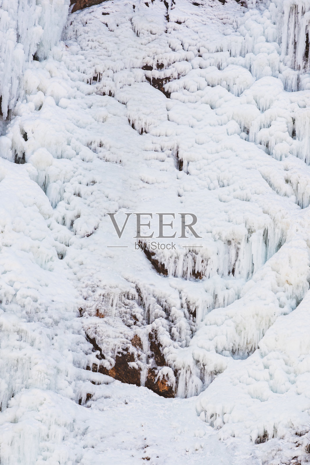 在寒冷的冬天结冰的瀑布。山悬崖照片摄影图片