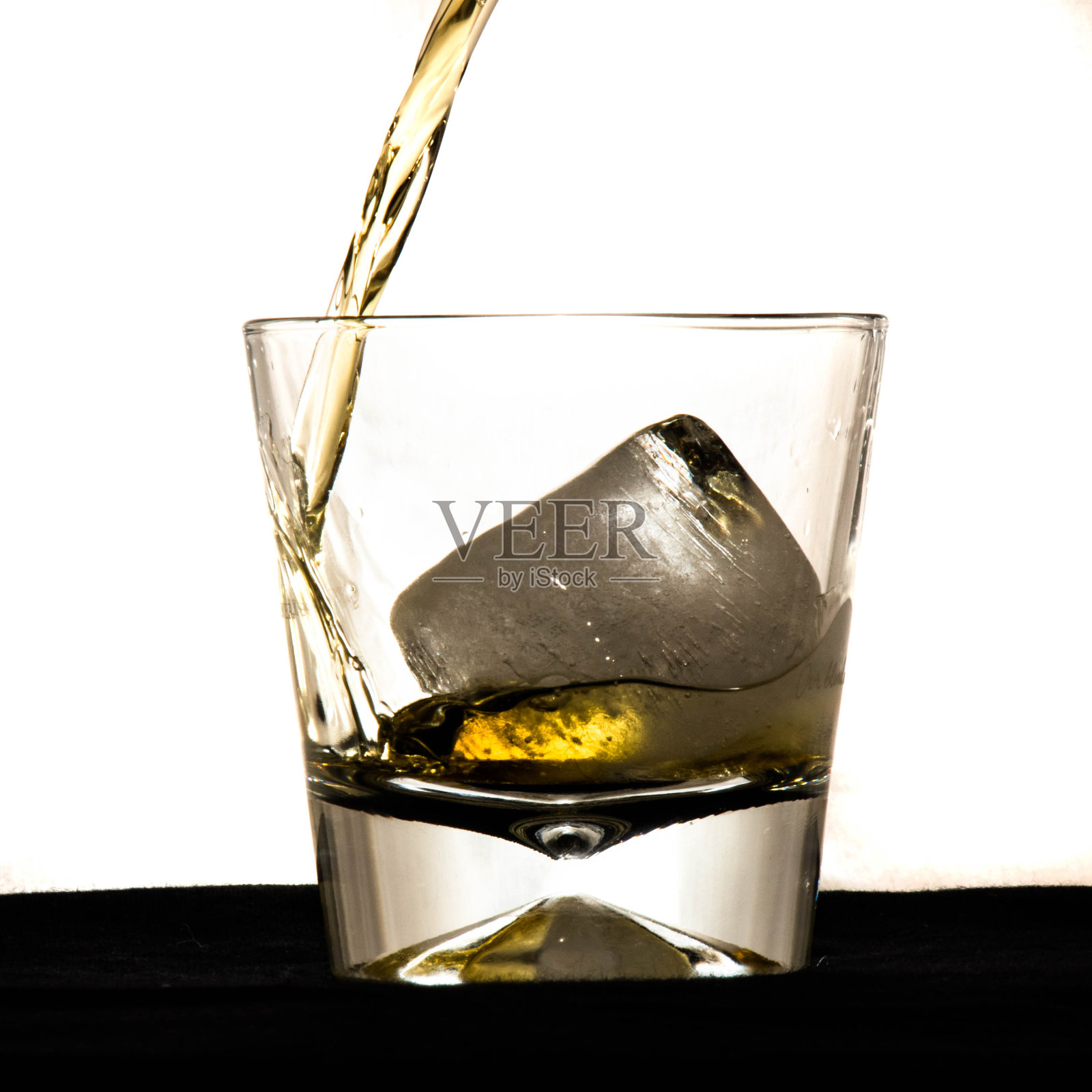 威士忌倒进杯子里。照片摄影图片