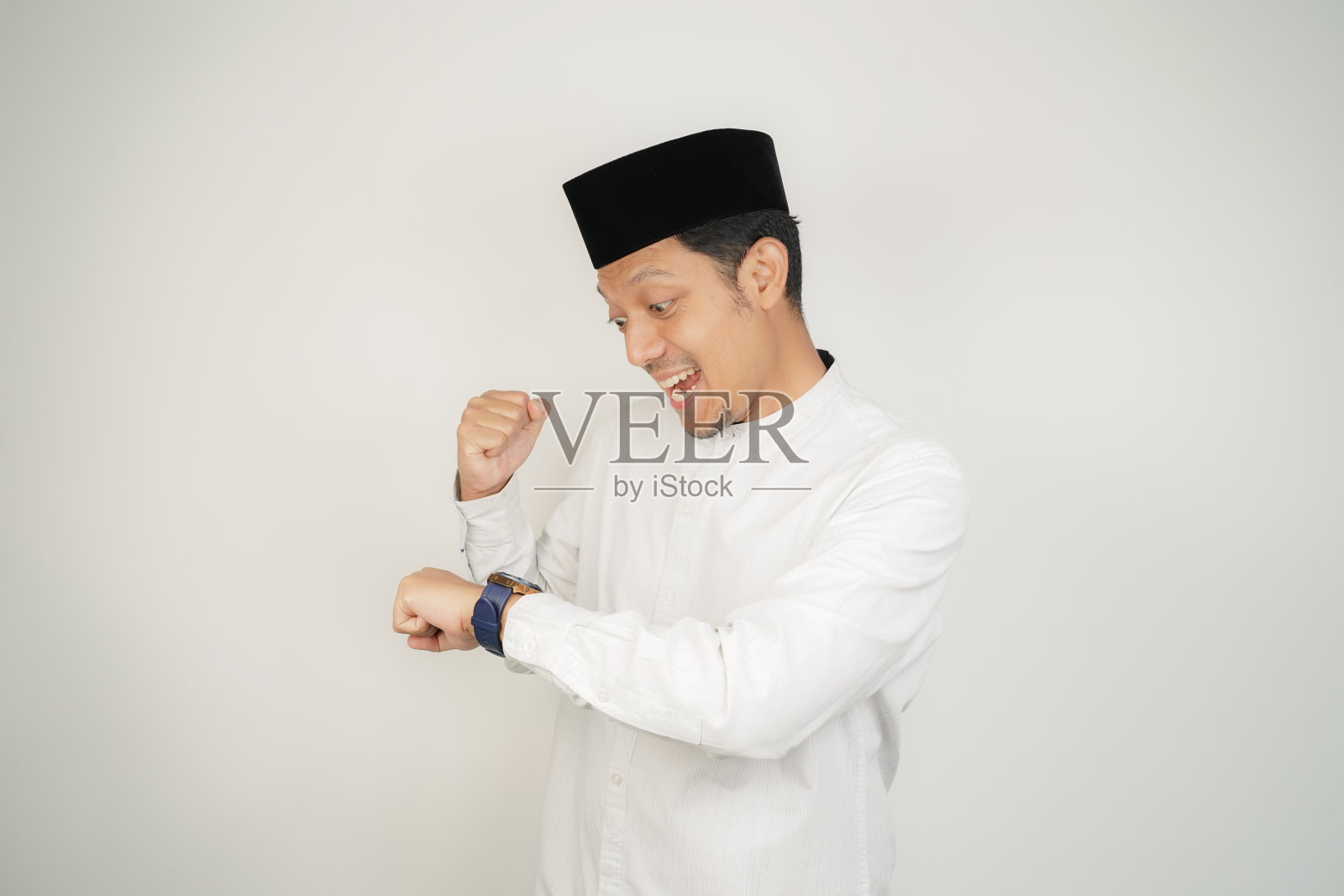 亚洲穆斯林男子兴奋的表情看着手表，穿着阿拉伯服装在复制空间孤立的背景照片摄影图片