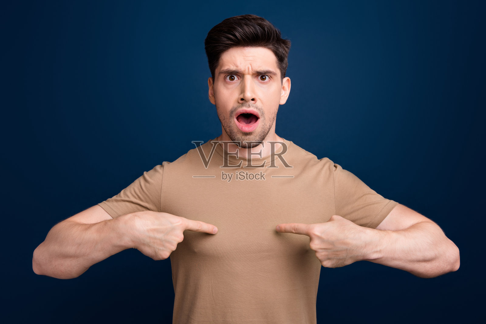 照片中，焦虑紧张、说不出话来的男子穿着时髦的衣服，指着自己的错误，失败被隔离在深蓝色的背景上照片摄影图片