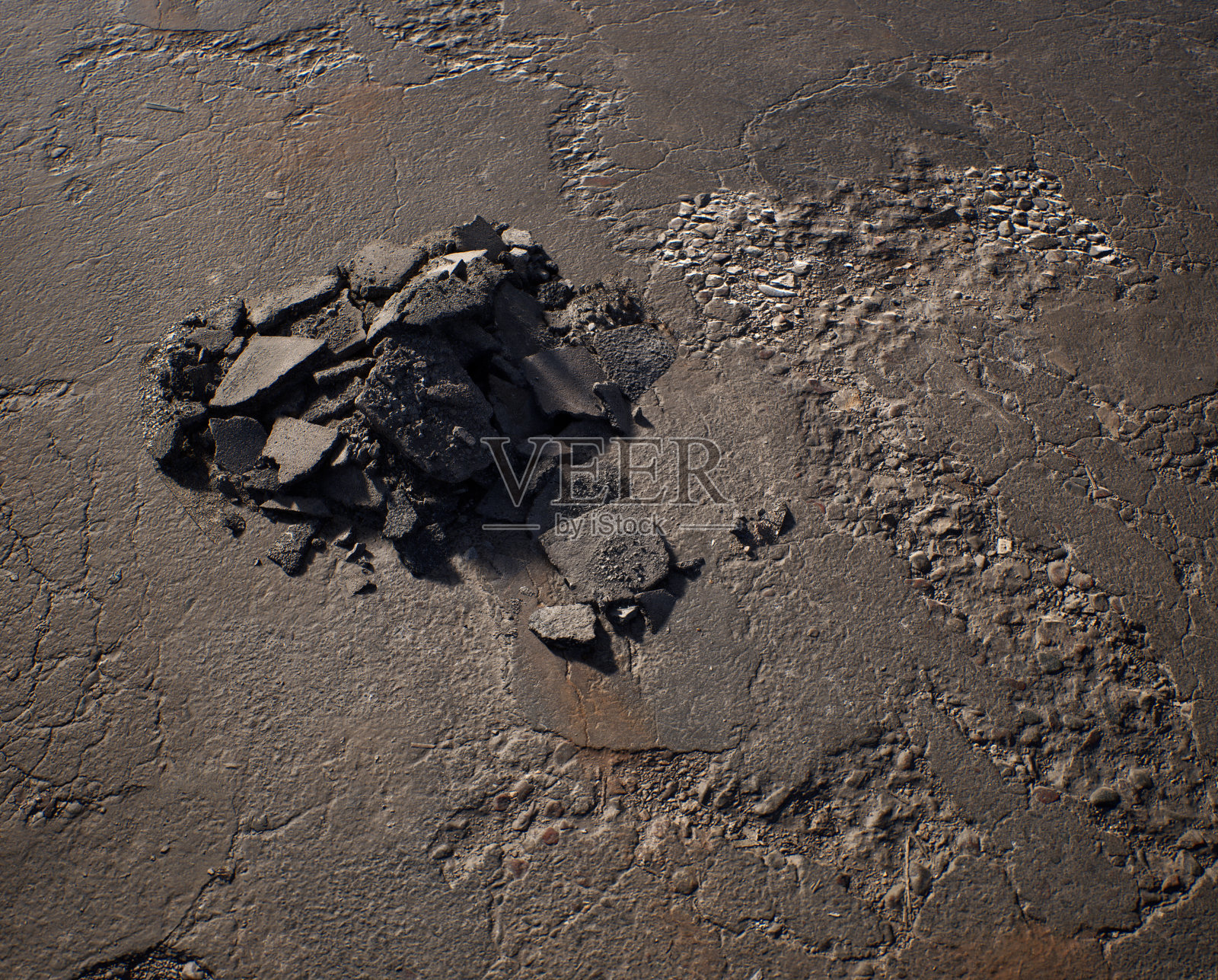 破旧的柏油路面上堆满了碎石。照片摄影图片