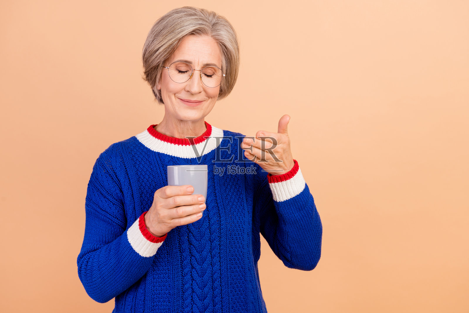 梦幻般的善良可爱的女人穿着时髦的蓝色衣服，在米色的背景上享受着天然咖啡的味道照片摄影图片