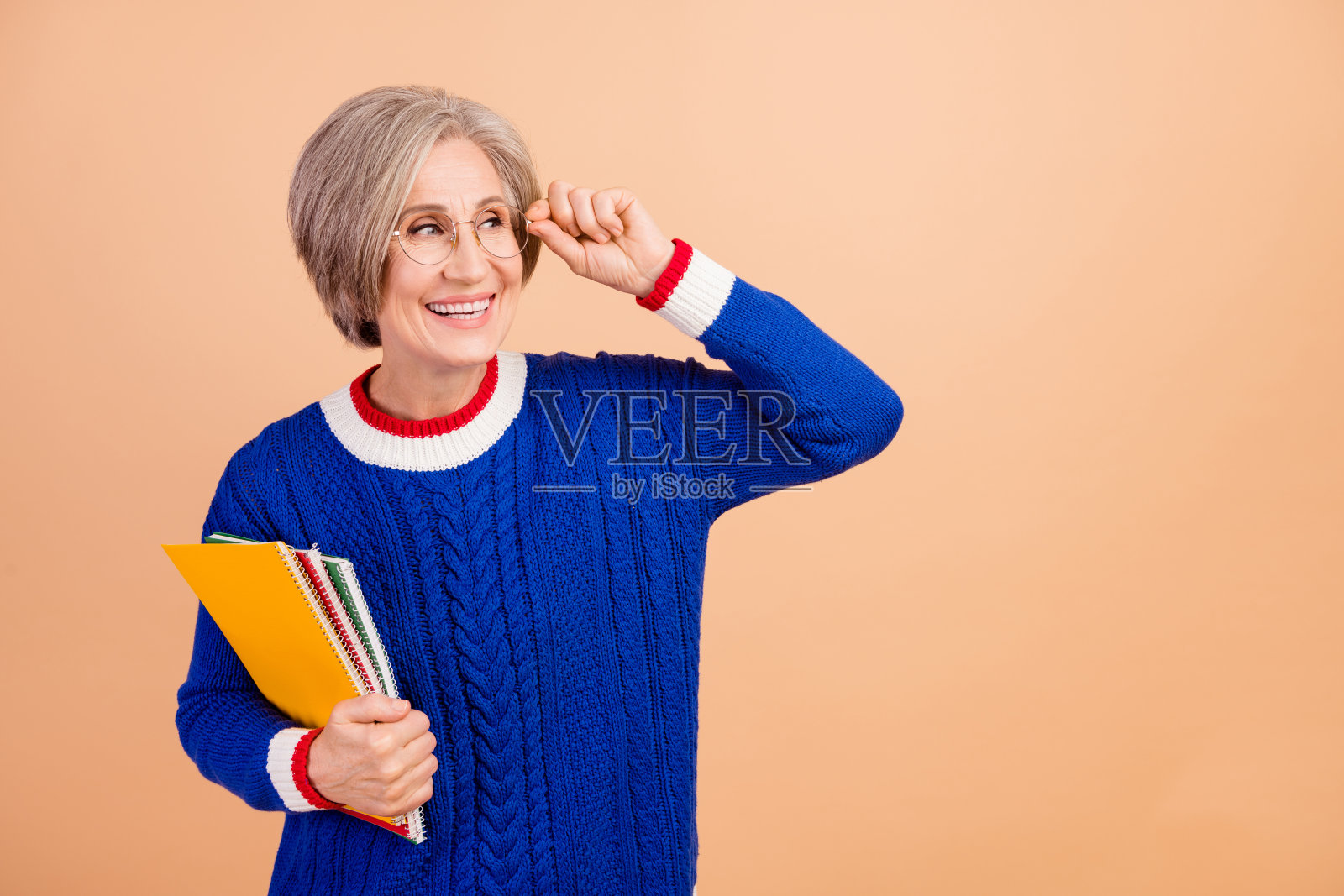 照片中迷人可爱的女士穿着蓝色时尚的衣服，在米色的背景下看起来很空旷照片摄影图片