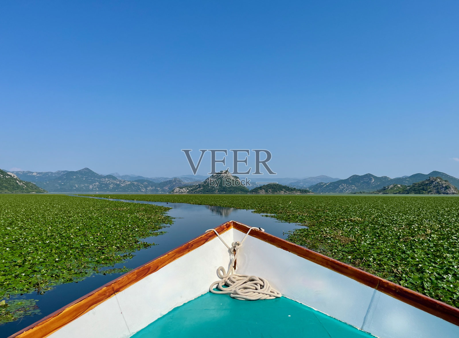 在美丽的斯卡达尔湖上划船，周围是绿色的山峰。黑山的斯卡达尔湖国家公园。照片摄影图片