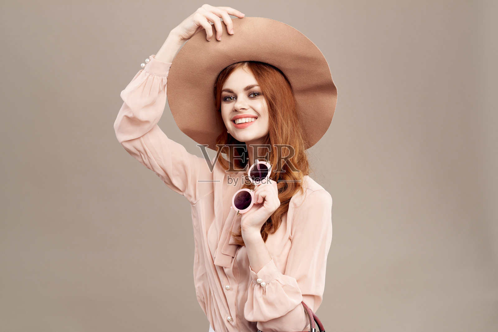 红头发的女人戴着帽子和衬衫，米色的背景化妆微笑魅力青春时尚照片摄影图片