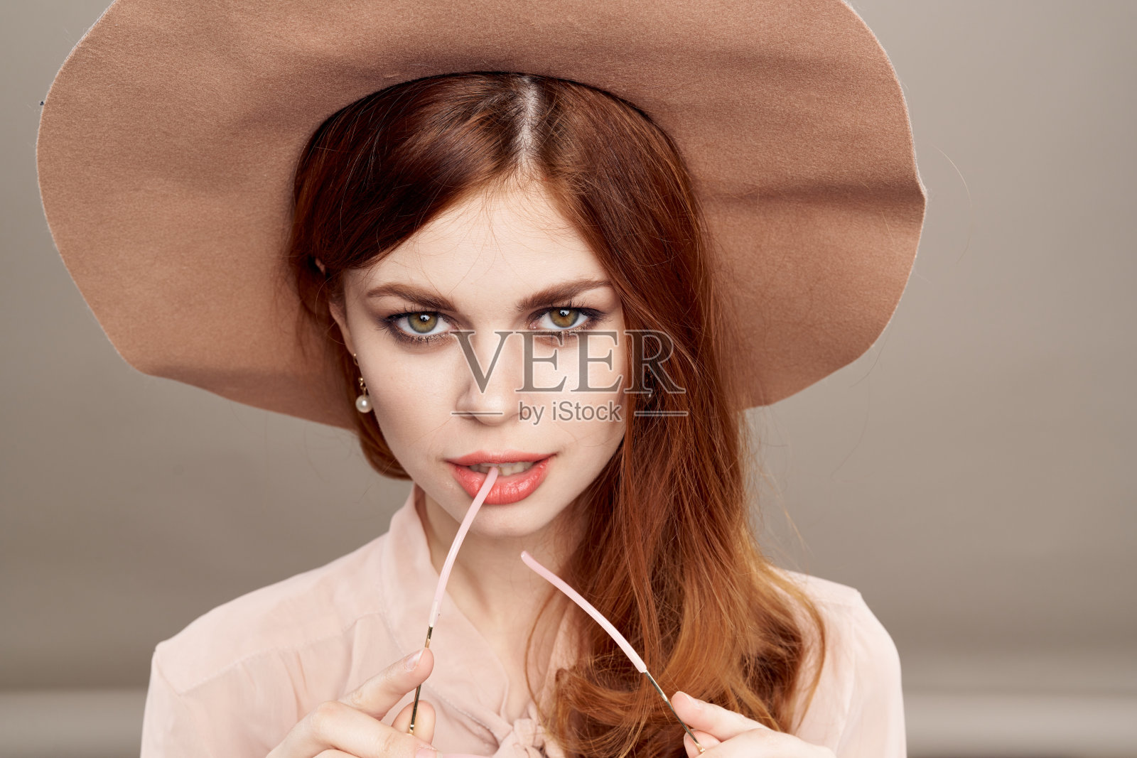 红头发的女人戴着帽子和衬衫，米色的背景化妆微笑魅力青春时尚照片摄影图片