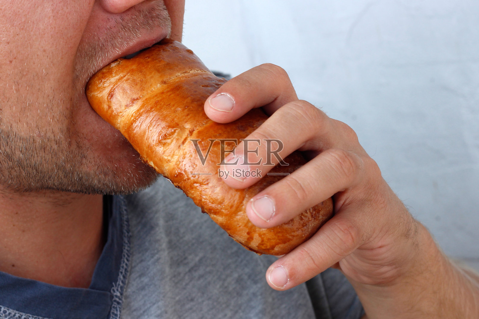 一个男人吃一个馒头，一个男人嘴咬一个馒头特写，营养概念照片摄影图片