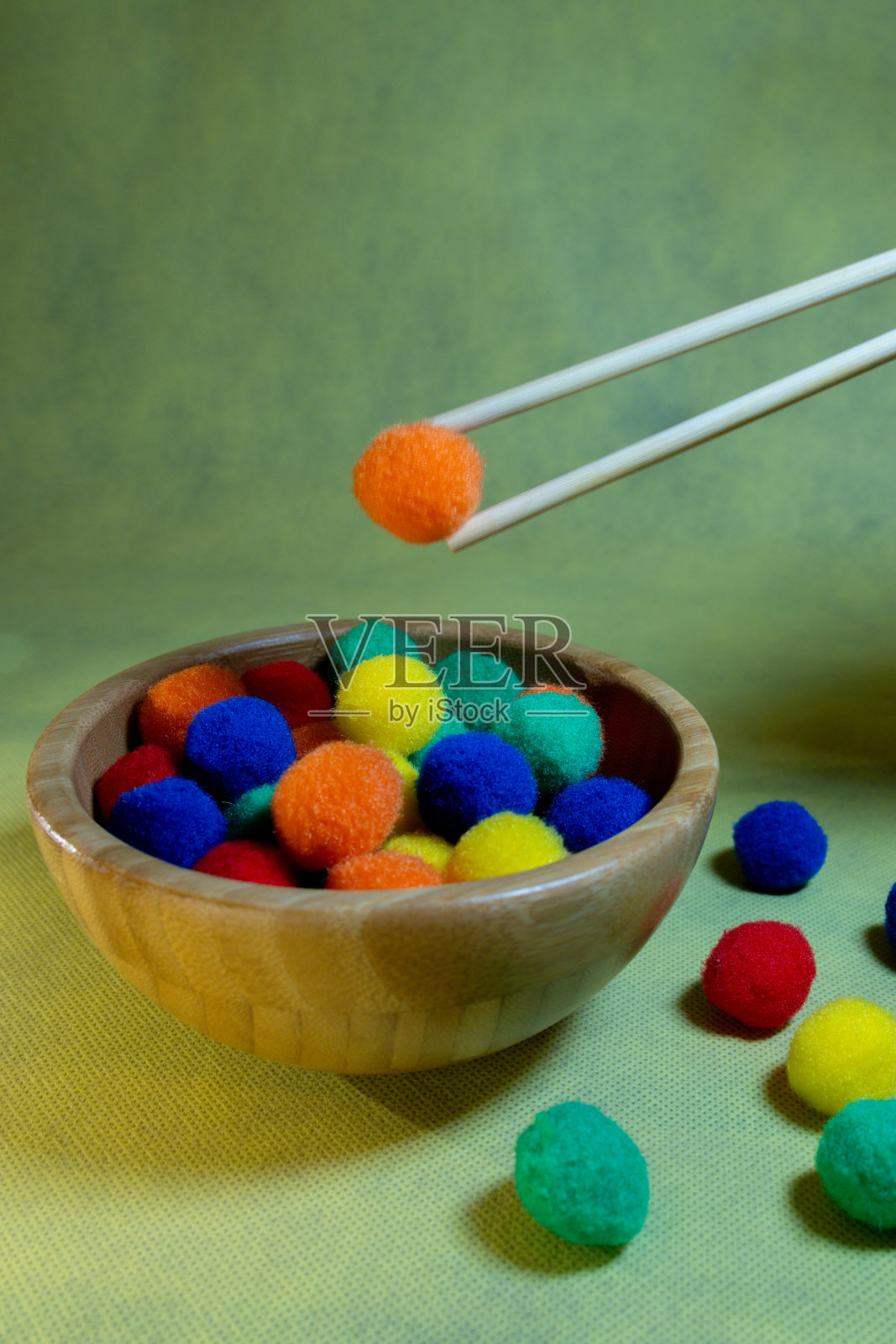 人学习如何使用筷子吃饭和练习用木碗与彩色球垂直图片照片摄影图片