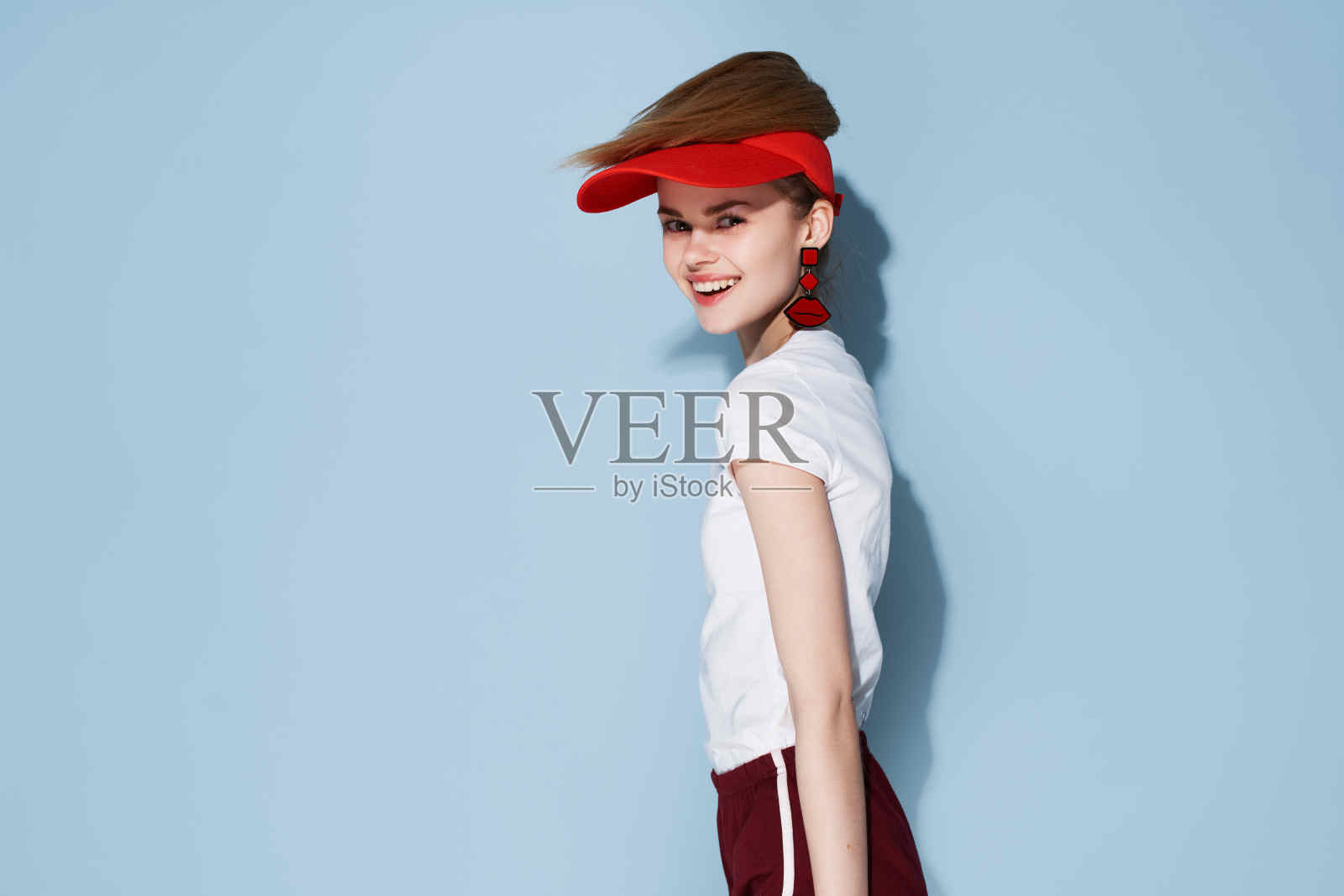 迷人的女孩戴着红帽，穿着夏装，摆着时尚的姿势照片摄影图片