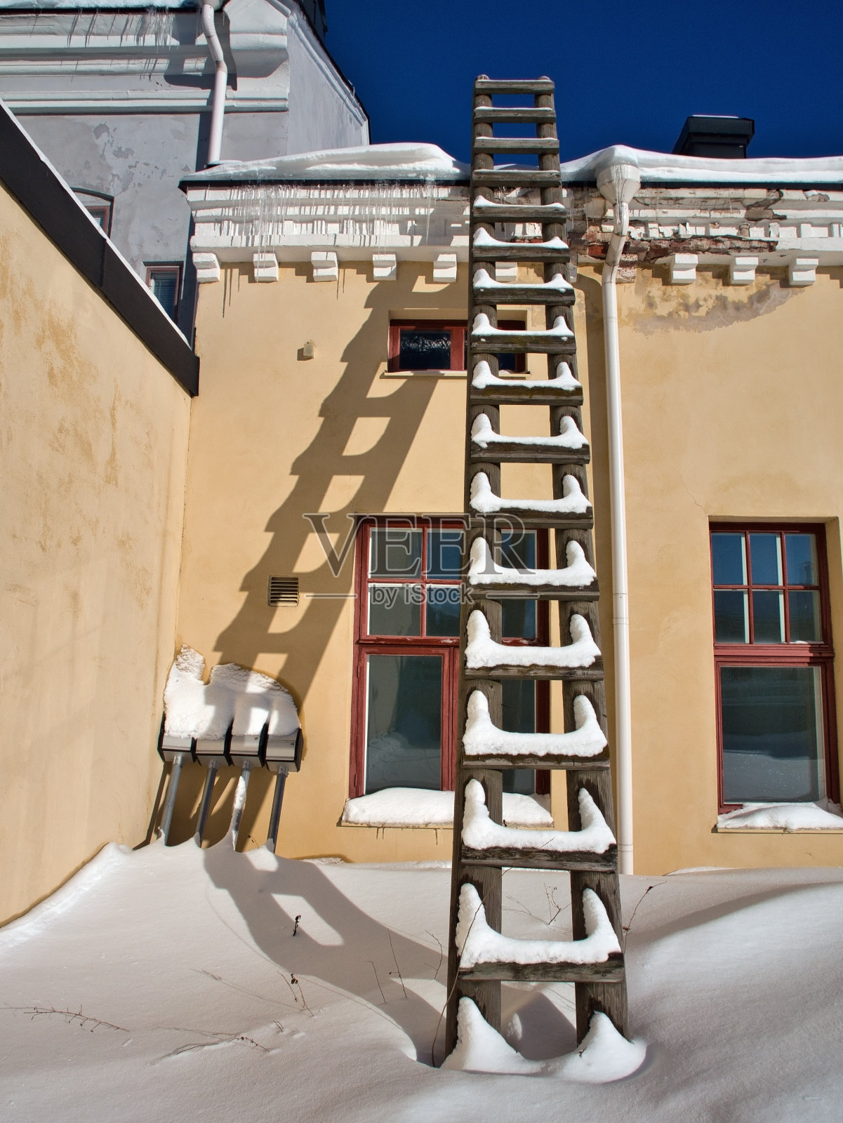 冬天靠在黄色墙壁上的木梯照片摄影图片