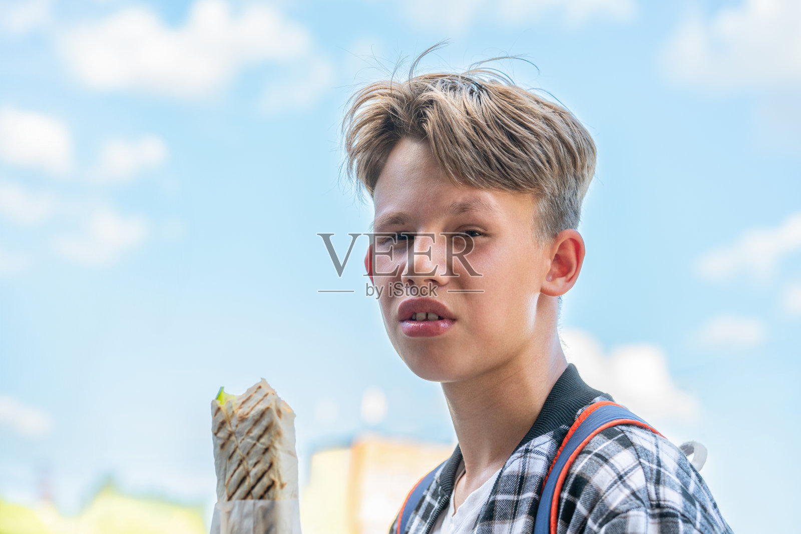 夏日里，金发少年在公园里享用鸡肉沙瓦玛照片摄影图片